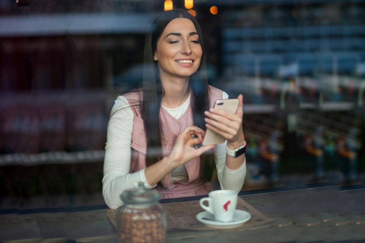 A smiling woman with a mobile and a coffee